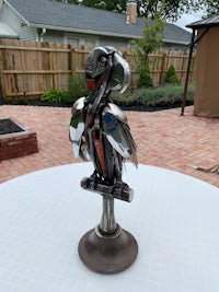 a sculpture of a parrot sitting on a table in a backyard