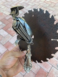 a person holding a metal bird on a saw blade