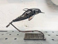 a metal sculpture of a dolphin on a stand