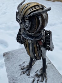a metal sculpture of an owl standing in the snow