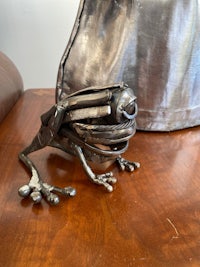 a silver frog sitting on top of a wooden table