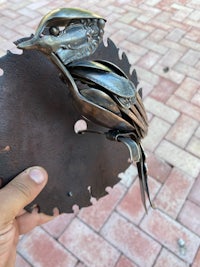 a person holding a metal sculpture of a bird