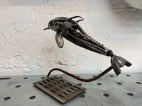 a metal sculpture of a dolphin on a stand